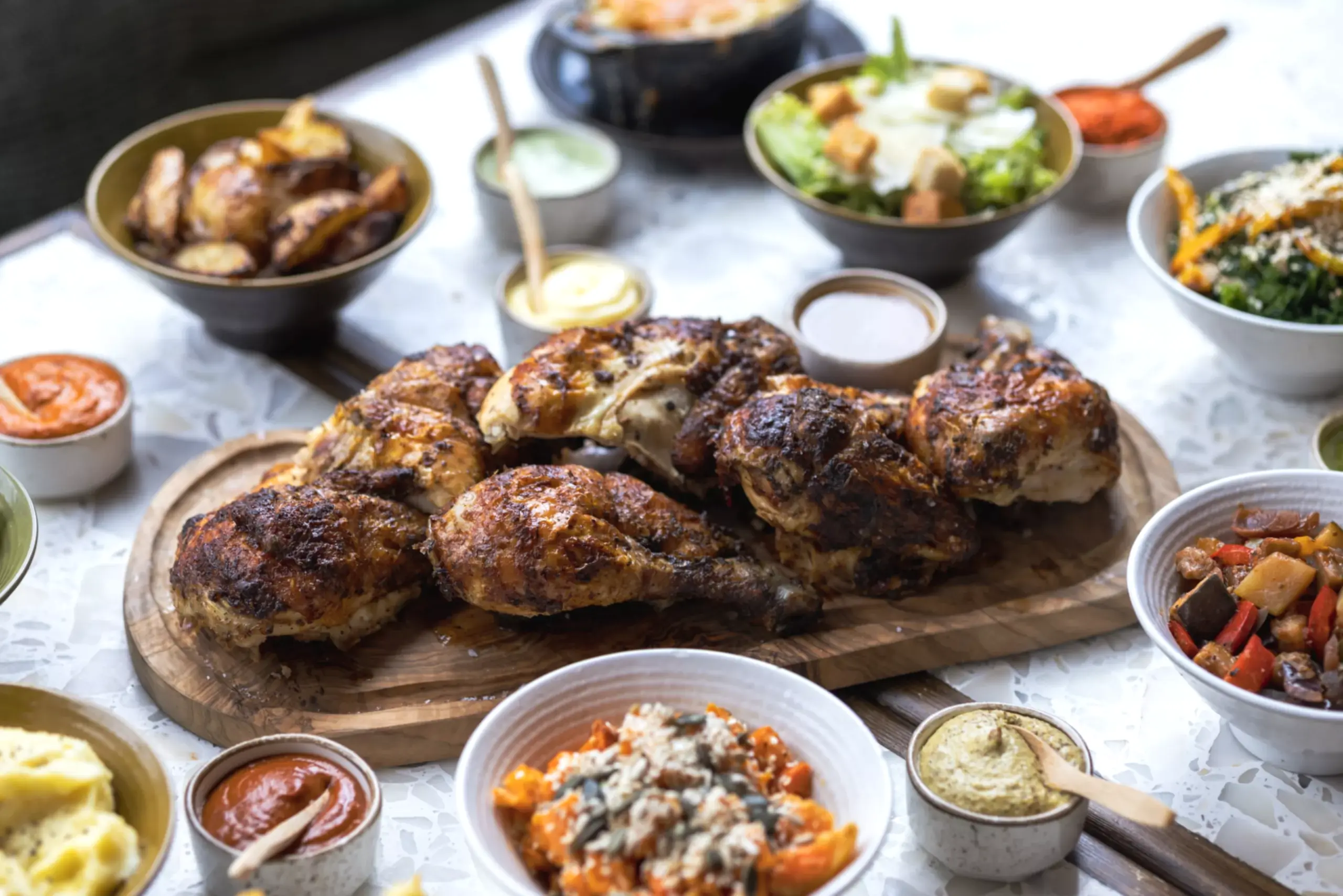 Rotisserie chicken on a table next to side dishes at Cocotte